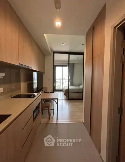 Modern apartment interior with sleek kitchen and view into cozy bedroom.