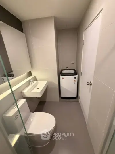 Modern bathroom with washing machine and sleek fixtures in a contemporary apartment.