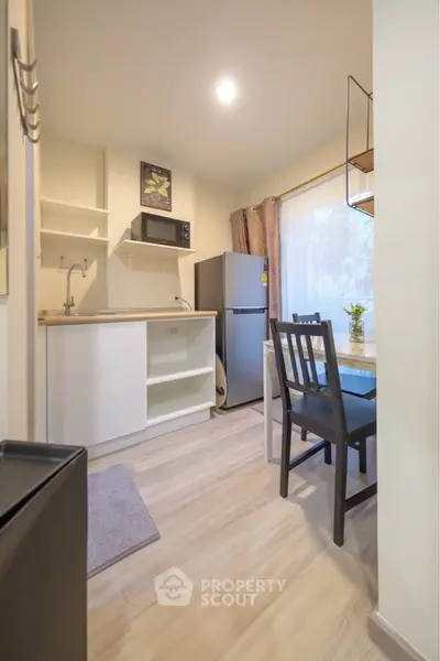 Modern kitchen with dining area, featuring fridge and microwave, ideal for compact living.