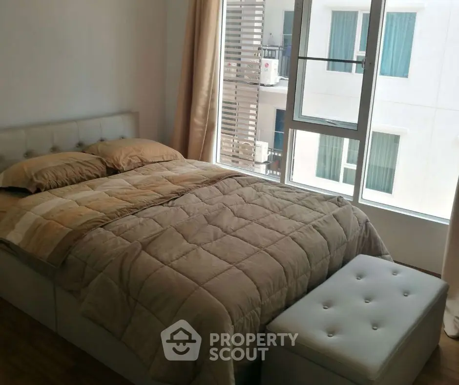 Cozy bedroom with modern decor and large window offering ample natural light.