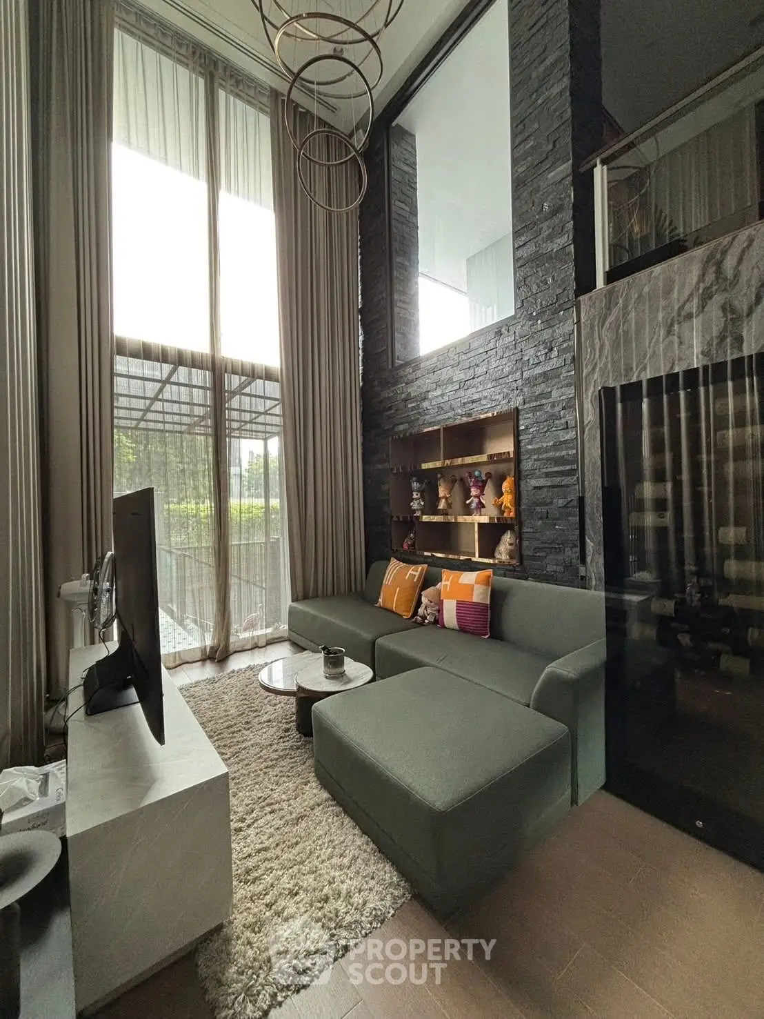 Modern living room with high ceilings and large windows, featuring a stylish sofa and elegant decor.