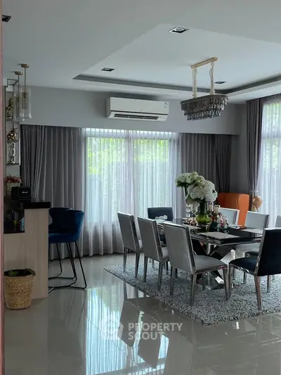 Elegant dining room with modern decor, large windows, and stylish chandelier in a spacious home.