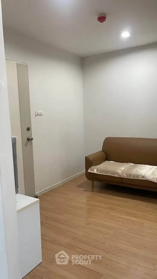 Cozy living room with wooden flooring and modern brown sofa, perfect for relaxation.