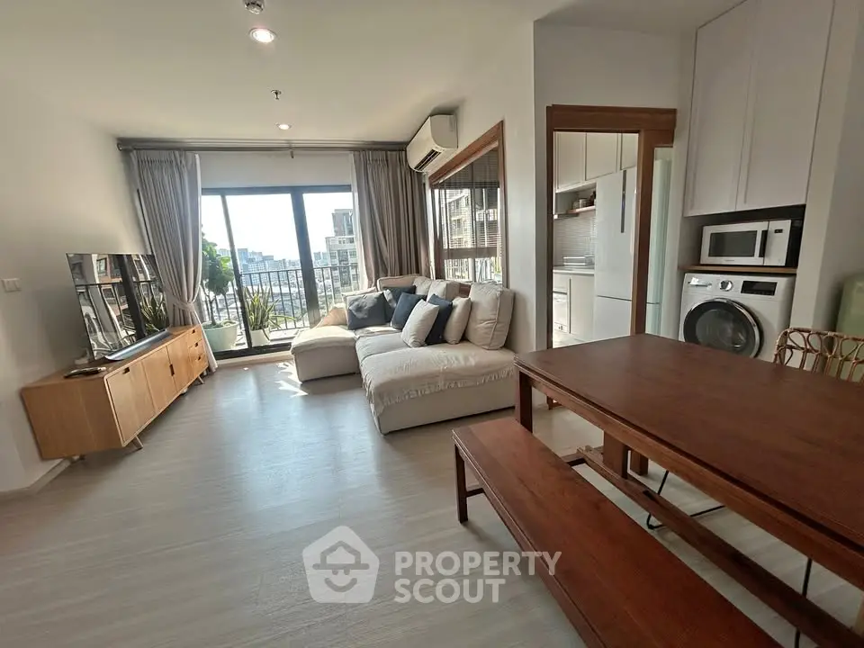 Spacious modern living room with balcony and city view, featuring cozy seating and dining area.