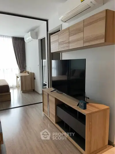 Modern living room with wooden furniture and large TV, featuring a sleek air conditioning unit.