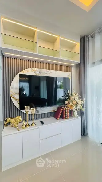 Elegant living room with modern decor, featuring a stylish TV unit, decorative shelves, and luxurious accents.