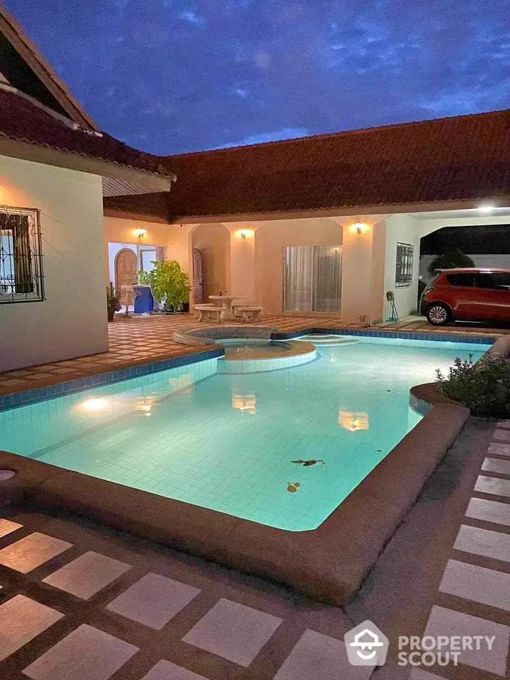 Charming villa with illuminated pool and spacious patio at dusk, perfect for relaxation and entertainment.