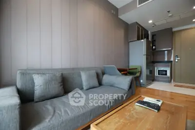 Modern living room with cozy gray sofa and compact kitchen area in stylish apartment.