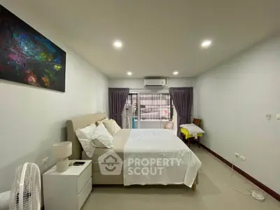 Spacious bedroom with modern decor and natural light, featuring a comfortable bed and stylish furnishings.