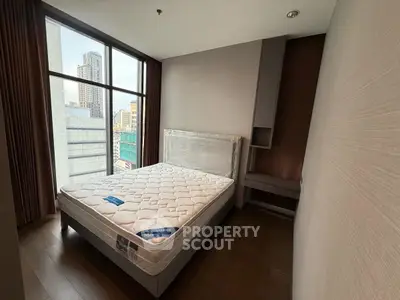 Modern bedroom with large window offering city view, featuring a new mattress and sleek design.