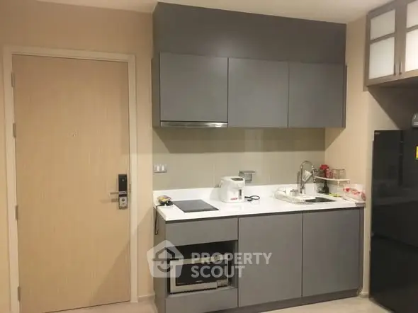 Modern compact kitchen with sleek gray cabinets and built-in appliances