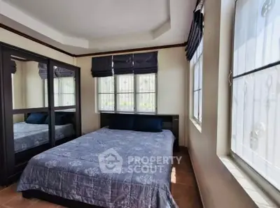 Cozy bedroom with large windows and mirrored wardrobe, perfect for natural light lovers.