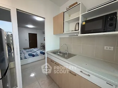 Modern kitchen with open layout and view into cozy bedroom