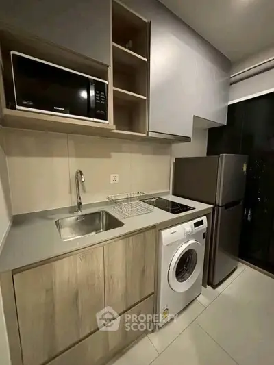 Modern kitchen with sleek appliances and compact design, featuring a washing machine and microwave.