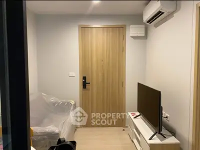 Cozy living room with modern decor, featuring a TV and air conditioning, perfect for relaxation.
