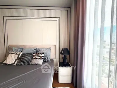 Modern bedroom with stylish decor and large window offering city views