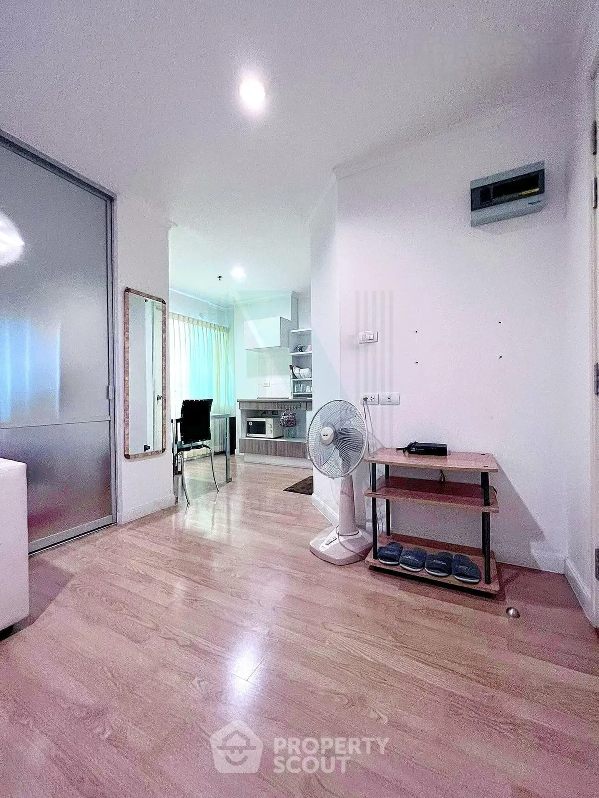 Modern open-plan living room with wooden flooring and compact kitchen area.