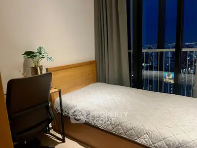 Modern bedroom with city view, featuring a cozy bed and stylish desk setup.