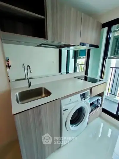 Modern kitchen with washing machine and sleek cabinetry in a bright apartment.