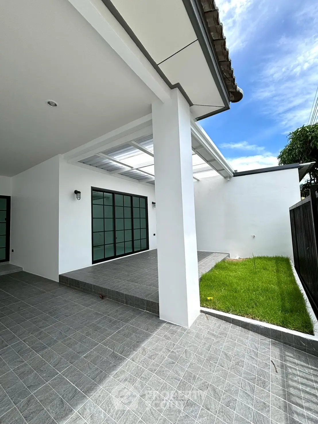Modern exterior with tiled patio and lush green lawn under a clear blue sky.