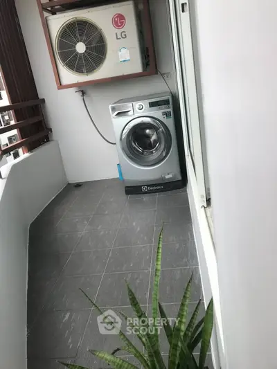 Modern balcony with washing machine and air conditioning unit, sleek design.