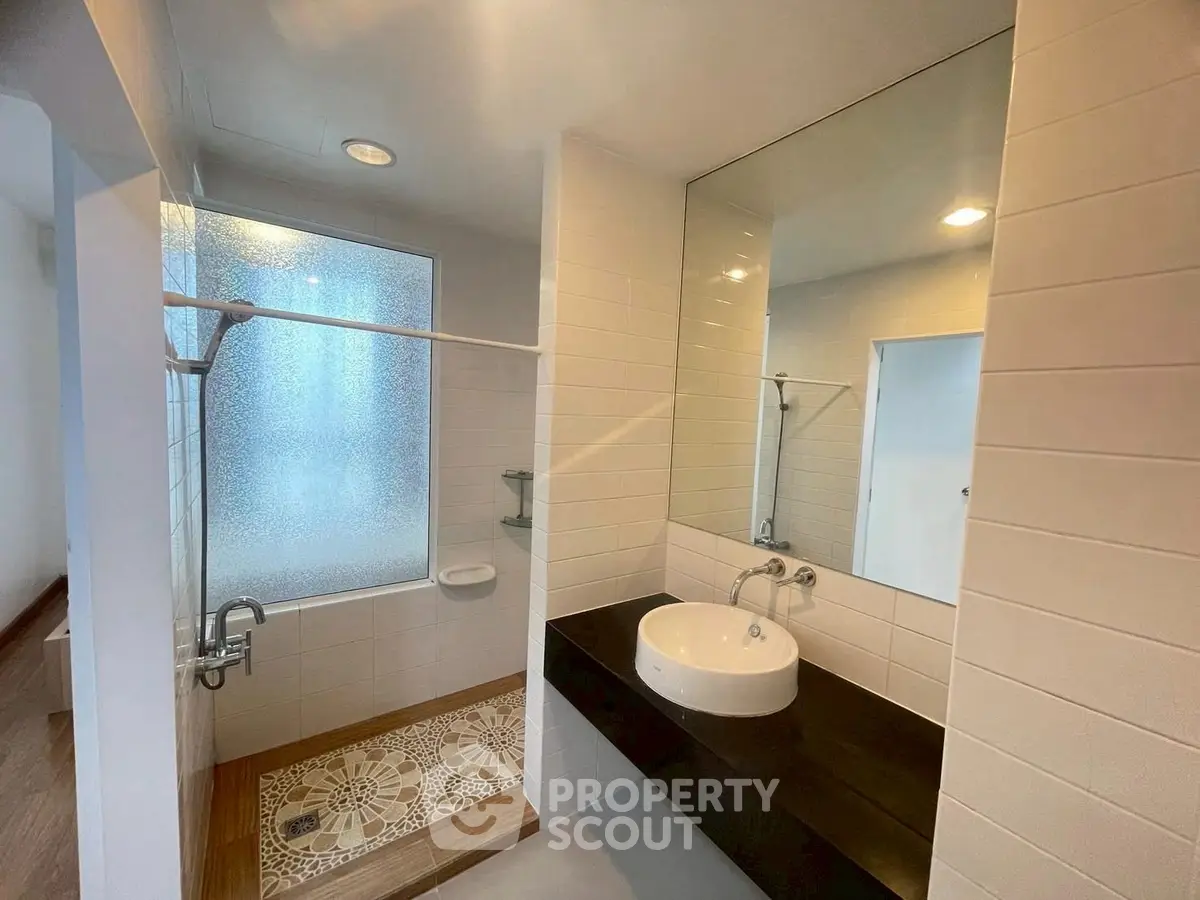 Modern bathroom with stylish sink and frosted glass shower in a contemporary home.