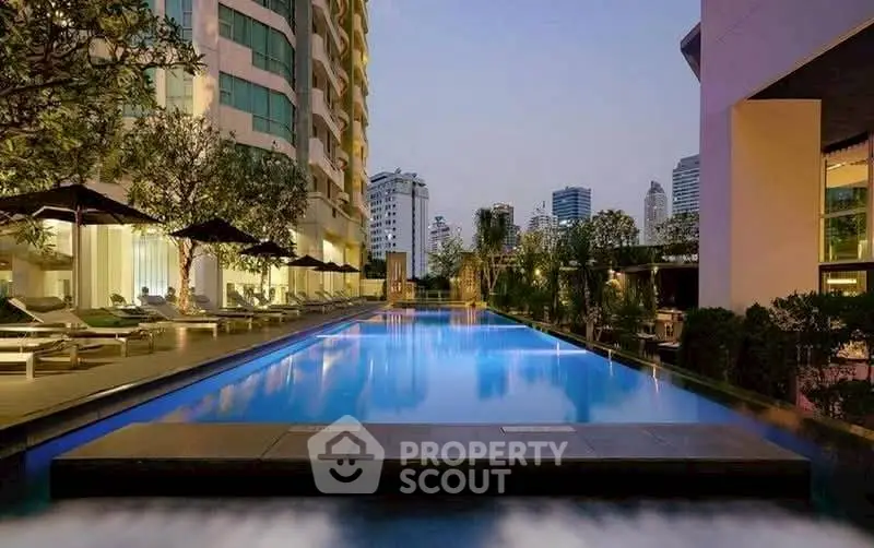 Luxurious high-rise building with stunning rooftop pool and city skyline view at dusk.