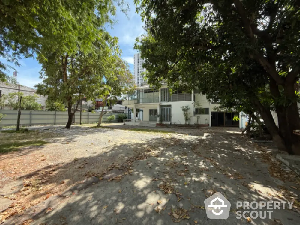 Spacious garden view with modern building and lush trees, perfect for serene living.