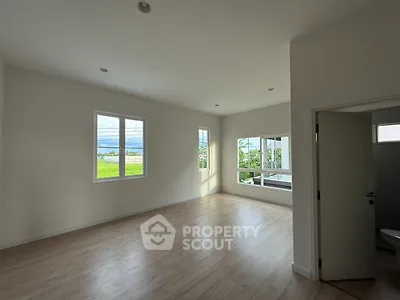 Spacious empty room with large windows and wooden flooring, perfect for customization.