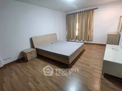 Spacious bedroom with wooden flooring and modern furniture in a cozy apartment.