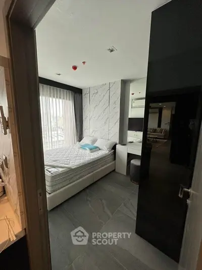 Modern bedroom with large window and stylish decor in a contemporary apartment.