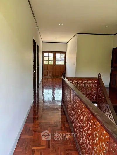 Elegant hallway with polished wooden floors and intricate railing design.
