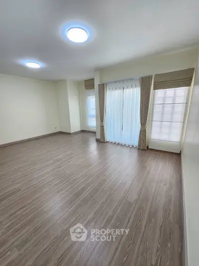 Spacious empty room with large windows and elegant curtains, perfect for customization.
