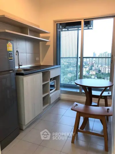 Modern kitchen with balcony view, featuring sleek cabinetry and compact dining set.