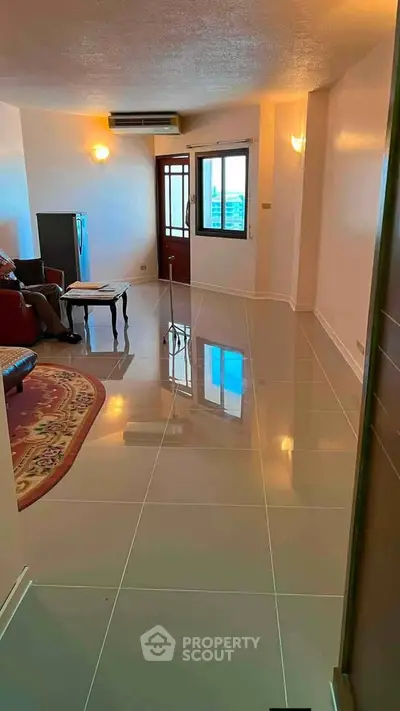 Spacious living room with glossy tiled floors and modern lighting, perfect for relaxation and entertainment.