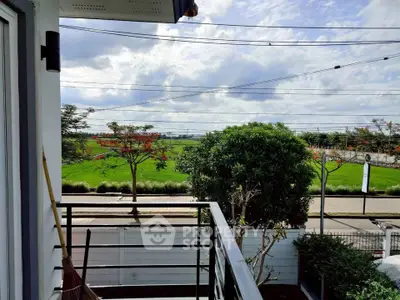 Charming balcony view overlooking lush greenery and open skies, perfect for relaxation.