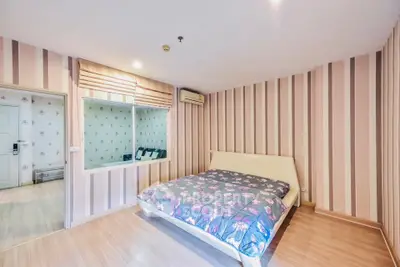 Spacious bedroom with stylish striped wallpaper and cozy bed in modern apartment.