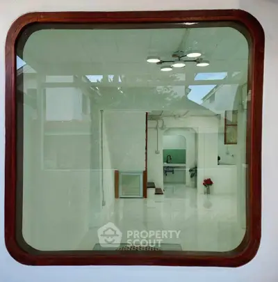 Modern interior view through large window with sleek kitchen design and marble flooring.
