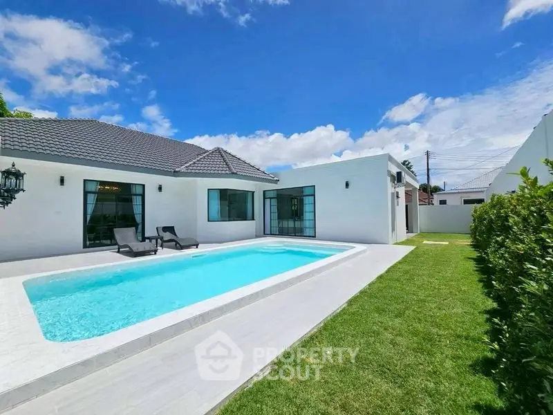 Luxurious modern villa with private pool and lush garden under clear blue sky.