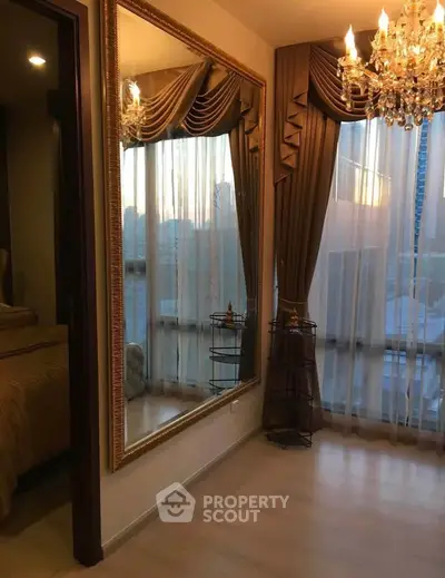 Luxurious bedroom with elegant chandelier and large mirror reflecting natural light.