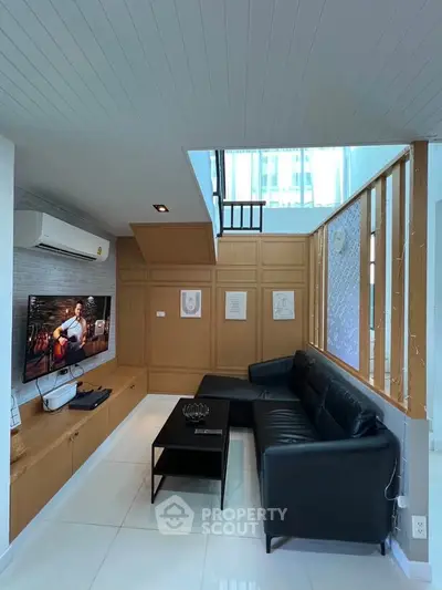 Modern living room with sleek black sofa, wall-mounted TV, and stylish wooden paneling.
