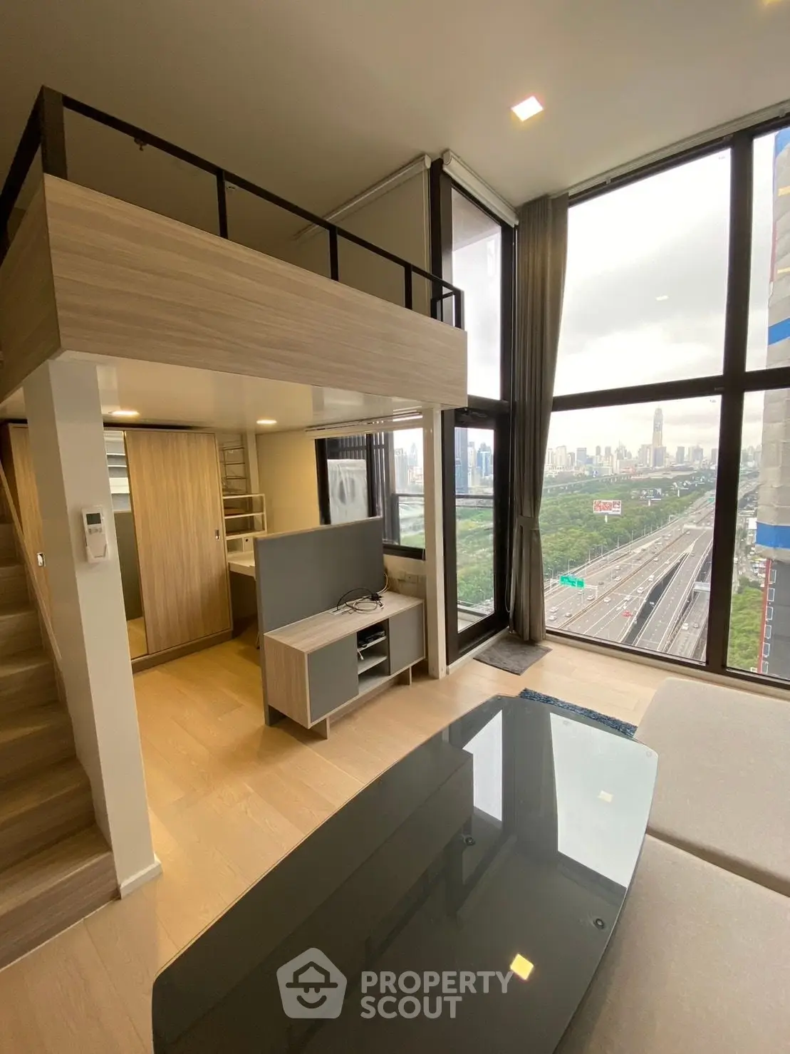 Modern loft apartment with large windows and city view, featuring a mezzanine and stylish interior design.