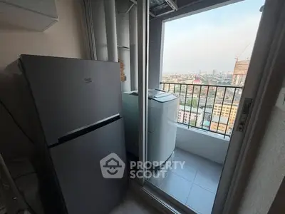 Compact balcony with city view, featuring a fridge and washing machine for urban living convenience.