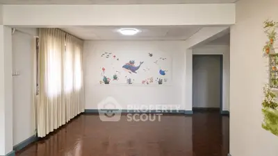 Spacious living room with wooden flooring and ocean-themed wall art, perfect for family gatherings.