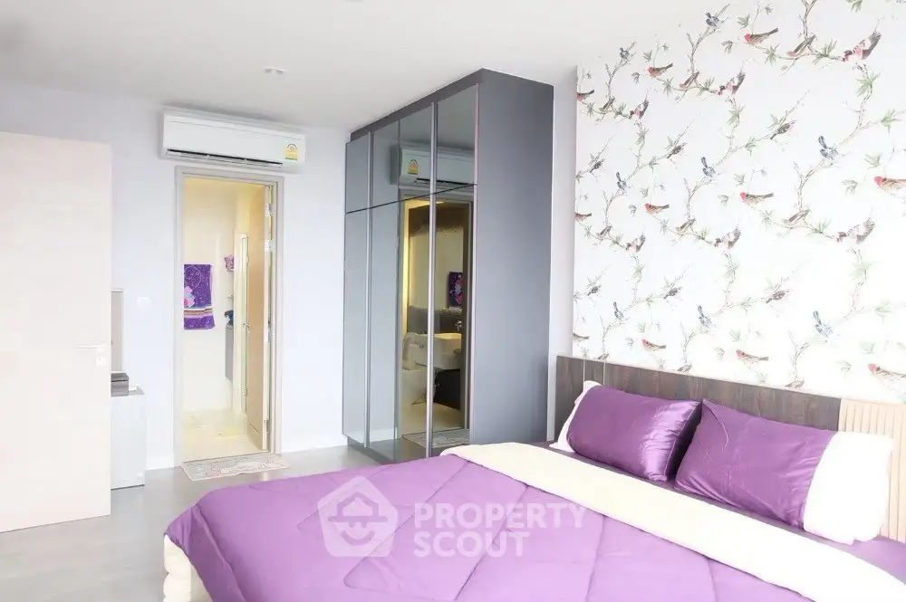 Modern bedroom with vibrant purple bedding and mirrored wardrobe
