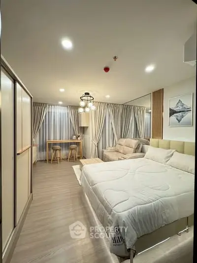 Spacious modern bedroom with elegant decor and cozy seating area.