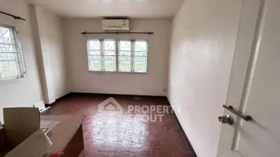 Spacious empty room with wooden flooring and large windows, ideal for customization.