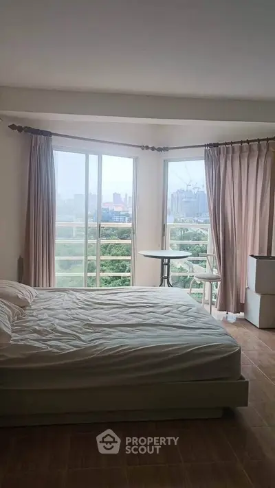 Spacious bedroom with large windows offering a stunning city view, perfect for urban living.