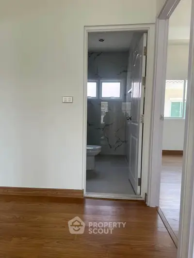 Spacious room with wooden flooring and en-suite bathroom in modern home.