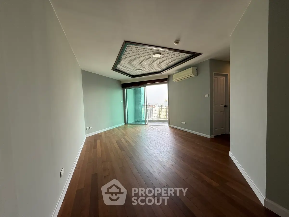 Spacious living room with wooden flooring and balcony access